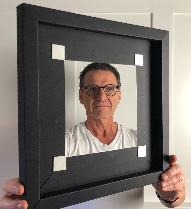 man looking through black paper frame