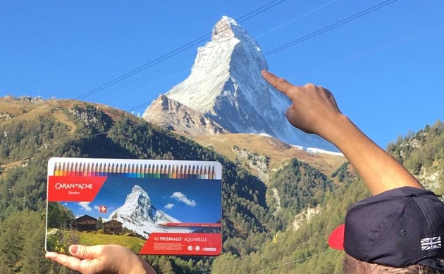 man pointing at snow capped Swiss mountain