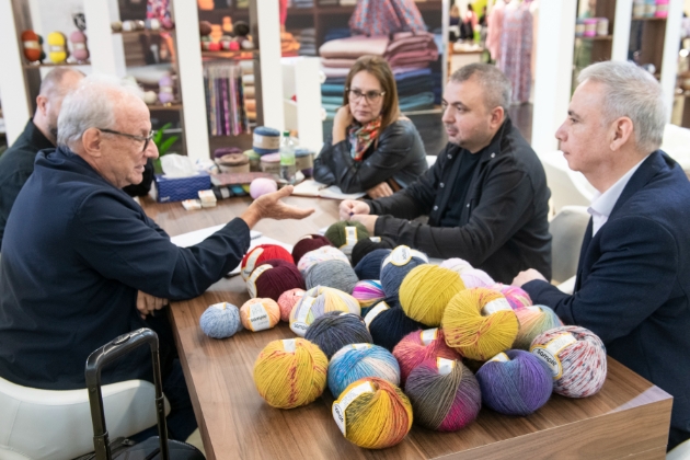 meeting around a small table full of balls of yarn