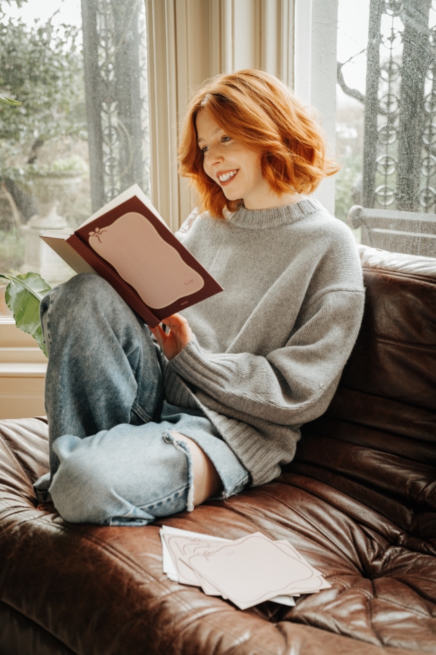 lady reading red and pink notebook on couch